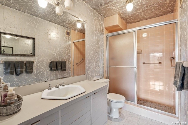 bathroom featuring tile patterned floors, vanity, toilet, and a shower with shower door