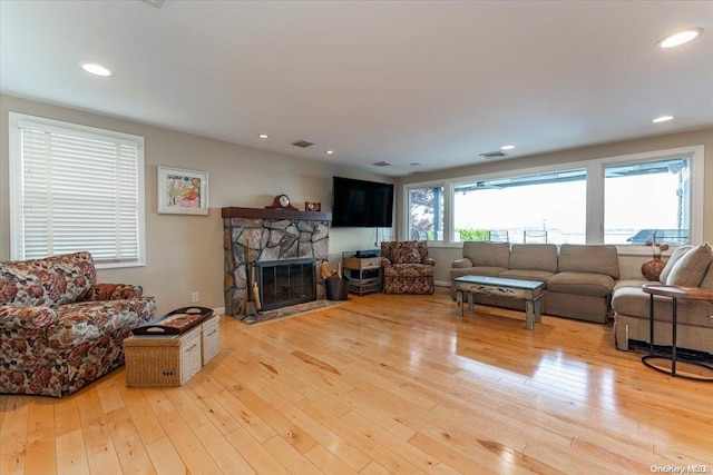 living room with light hardwood / wood-style flooring and a stone fireplace