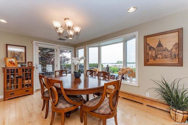 dining space with light hardwood / wood-style floors, a wealth of natural light, and a chandelier