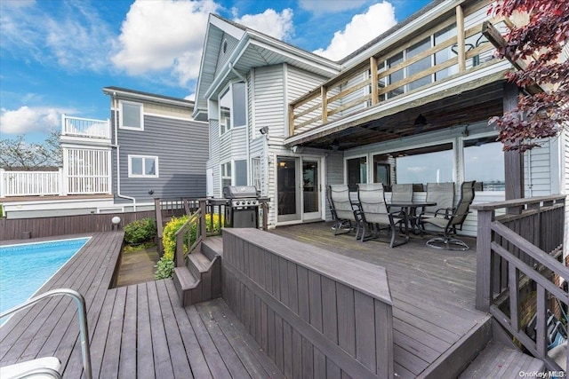 wooden deck featuring a fenced in pool and a grill