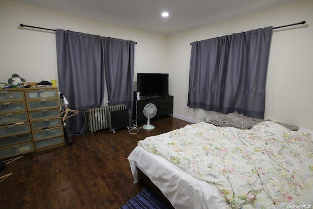 bedroom with radiator heating unit and dark hardwood / wood-style flooring