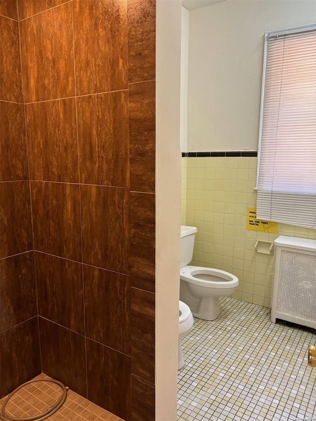 bathroom with tile patterned floors, toilet, radiator heating unit, and tile walls