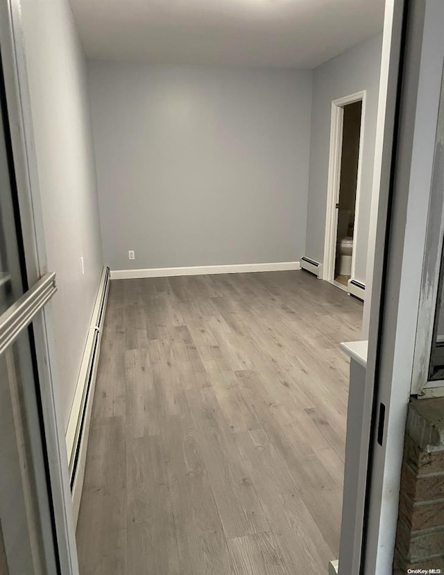 unfurnished room with light wood-type flooring and a baseboard radiator