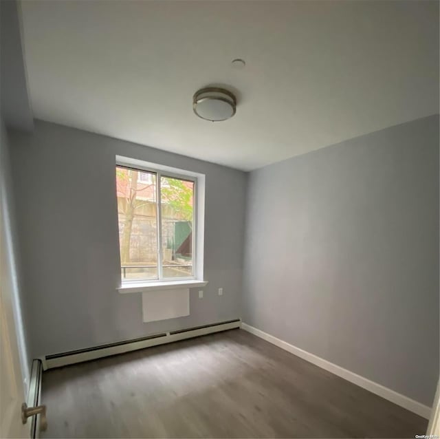 unfurnished room with wood-type flooring and a baseboard heating unit