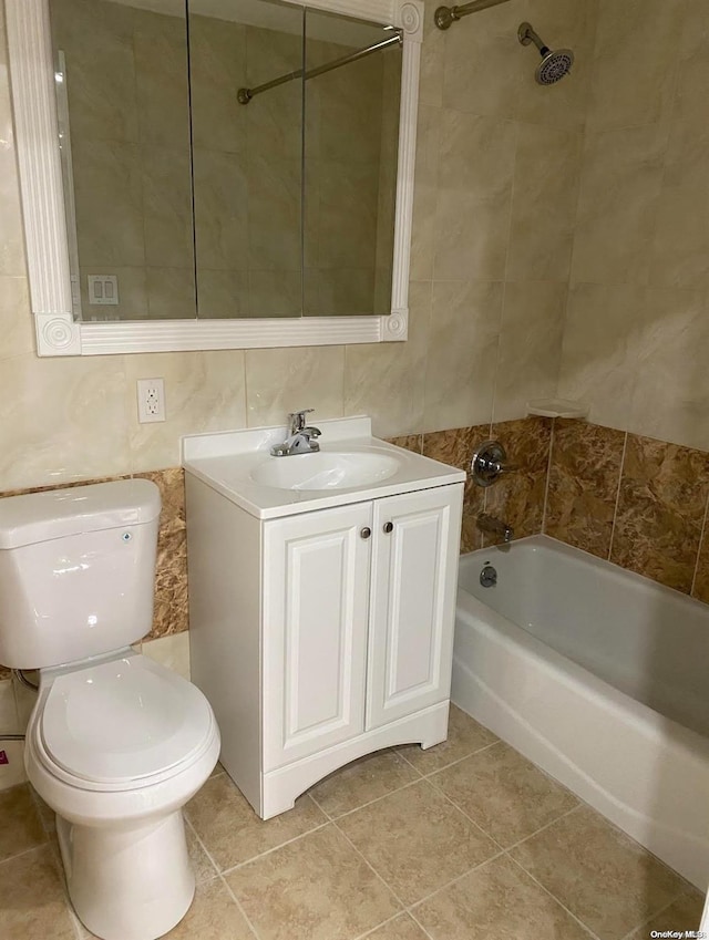 full bathroom with tile patterned floors, tiled shower / bath combo, tile walls, and vanity