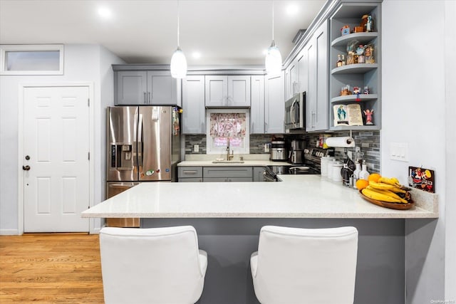 kitchen featuring pendant lighting, tasteful backsplash, a kitchen bar, kitchen peninsula, and stainless steel appliances