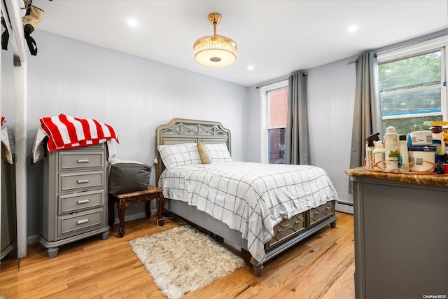 bedroom with light hardwood / wood-style floors and a baseboard radiator