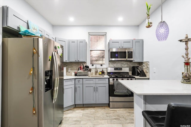 kitchen featuring sink, stainless steel appliances, tasteful backsplash, pendant lighting, and gray cabinets