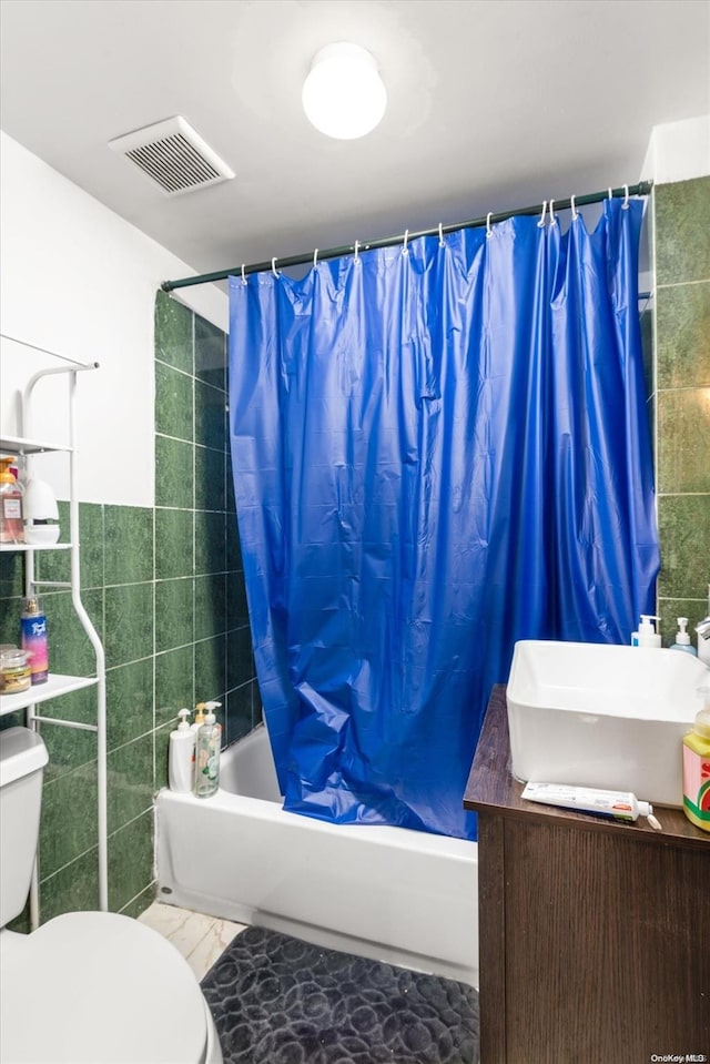 full bathroom featuring sink, tile patterned flooring, toilet, shower / bath combo with shower curtain, and tile walls