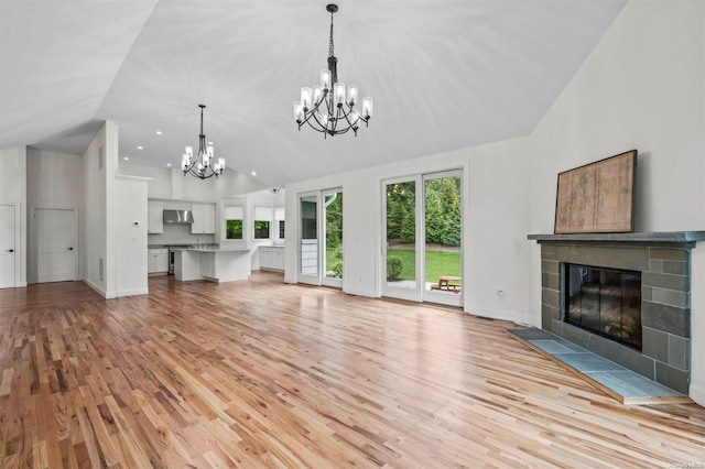 200 Cleft Rd, Mill Neck, NY 11765 - unfurnished living room featuring a chandelier, a tiled fireplace, light wood finished floors, high vaulted ceiling, and baseboards