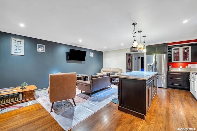 kitchen featuring light hardwood / wood-style flooring, stainless steel fridge, light stone countertops, decorative light fixtures, and a kitchen island