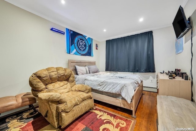 bedroom featuring baseboard heating and hardwood / wood-style floors