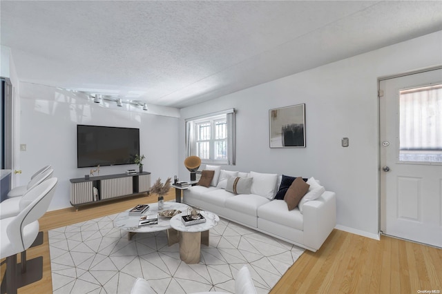 living room featuring plenty of natural light, a textured ceiling, and light hardwood / wood-style flooring