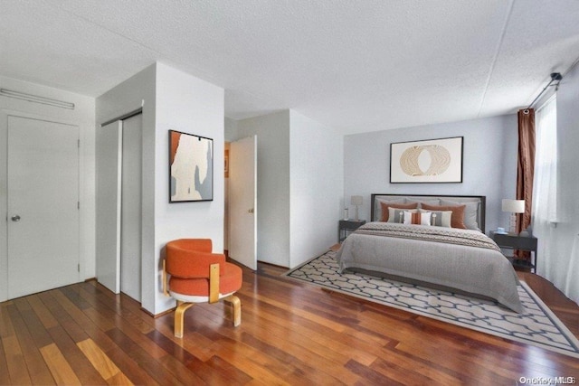 bedroom with a textured ceiling and dark hardwood / wood-style floors