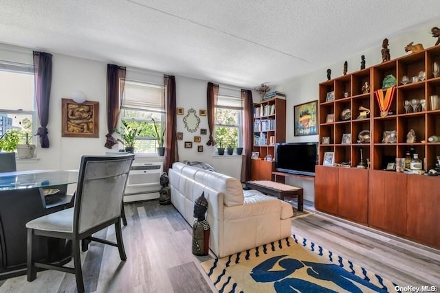 living room with a textured ceiling, a baseboard radiator, and light hardwood / wood-style flooring