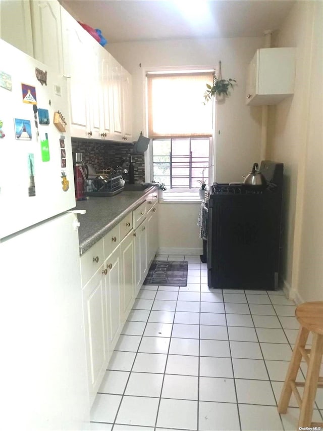 kitchen with white cabinets, white fridge, light tile patterned floors, and tasteful backsplash