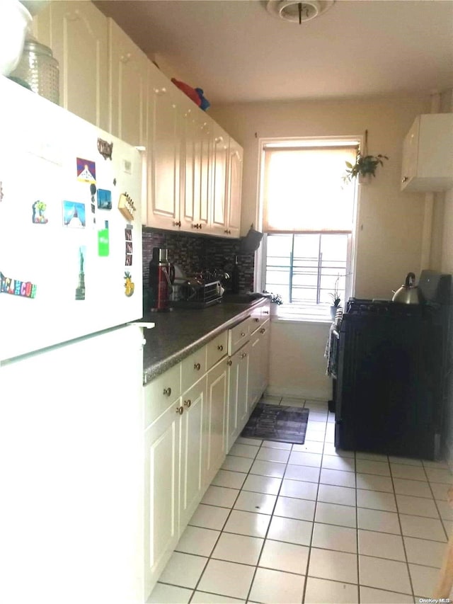 kitchen with white cabinets, white refrigerator, light tile patterned floors, and tasteful backsplash