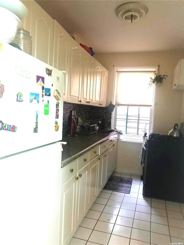 kitchen featuring tasteful backsplash, white cabinets, light tile patterned flooring, and white refrigerator