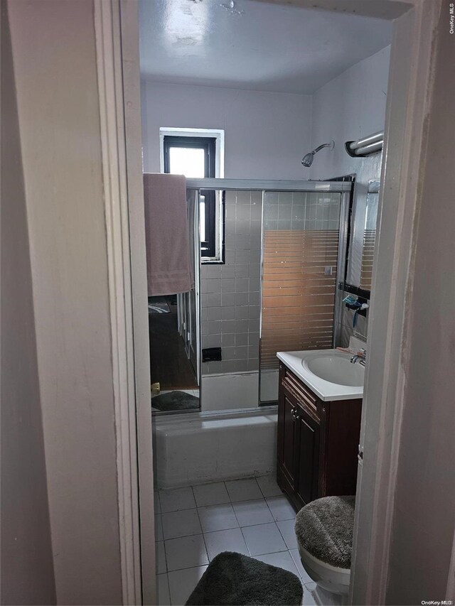 full bathroom featuring shower / bath combination with glass door, tile patterned flooring, vanity, and toilet