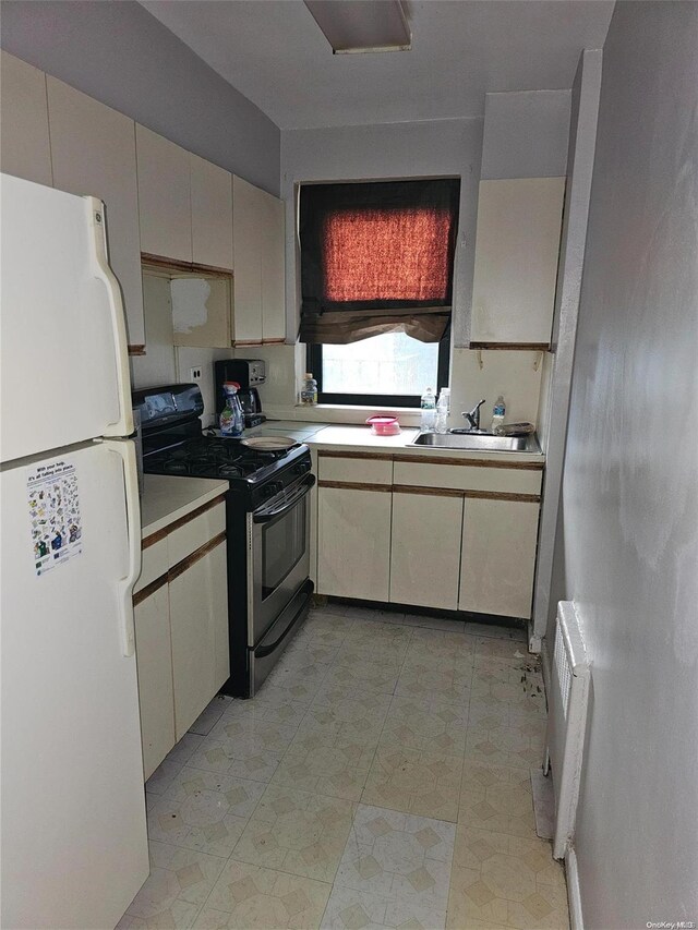 kitchen featuring electric range, white fridge, sink, and radiator