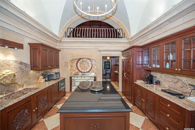 kitchen with a center island, stainless steel microwave, crown molding, and high vaulted ceiling