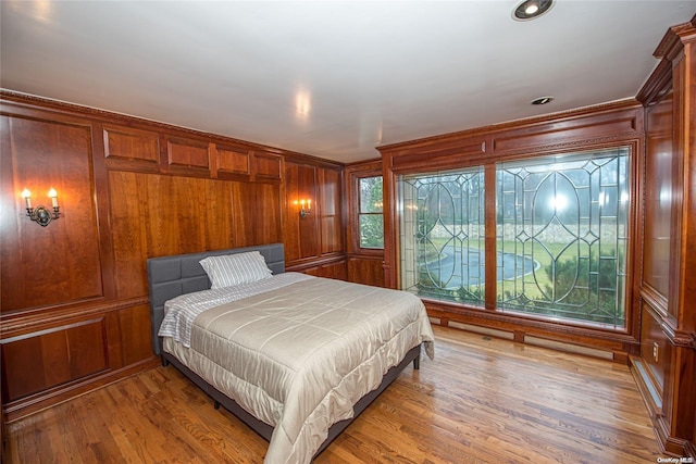 bedroom with light hardwood / wood-style floors and wooden walls