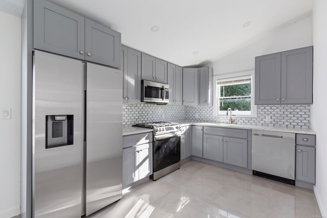 kitchen featuring decorative backsplash, sink, lofted ceiling, and stainless steel appliances