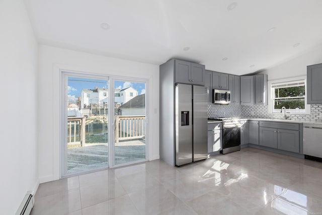 kitchen featuring baseboard heating, gray cabinetry, vaulted ceiling, and appliances with stainless steel finishes