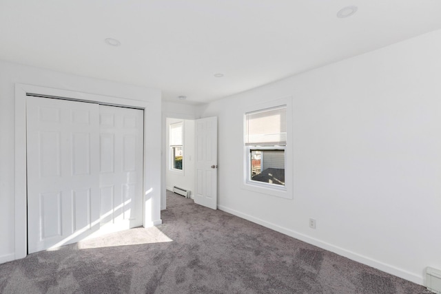 unfurnished bedroom with carpet, a closet, and a baseboard radiator