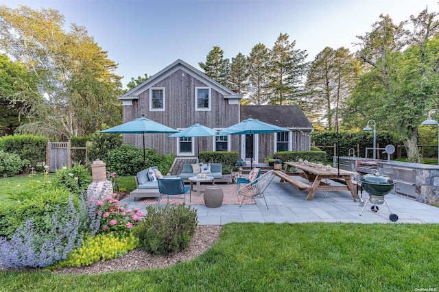 rear view of property featuring an outdoor living space, a yard, and a patio