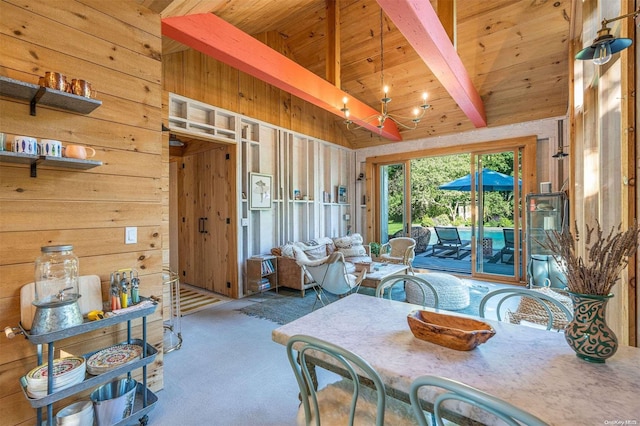 dining room featuring a chandelier, beam ceiling, carpet floors, and wood walls