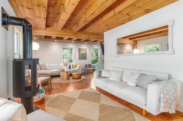 living room with beam ceiling, a wood stove, wood ceiling, and wood-type flooring