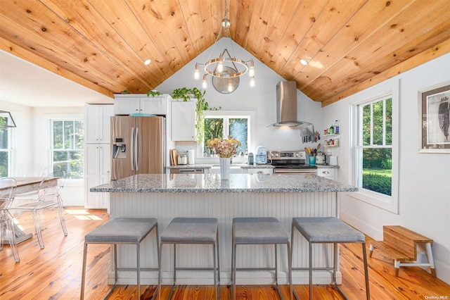 kitchen featuring light hardwood / wood-style floors, wall chimney range hood, white cabinetry, and appliances with stainless steel finishes