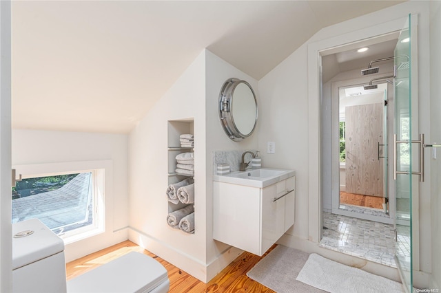 bathroom featuring a healthy amount of sunlight, wood-type flooring, vaulted ceiling, and washer / dryer