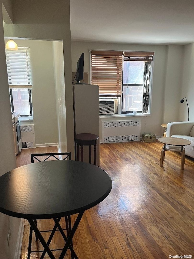 dining room with radiator heating unit, cooling unit, and hardwood / wood-style floors