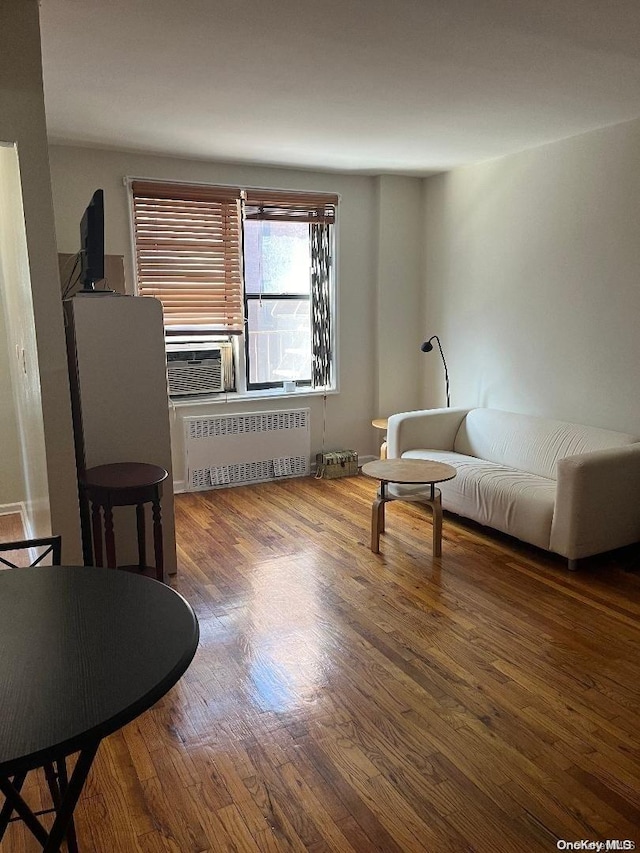 sitting room with radiator heating unit and hardwood / wood-style floors