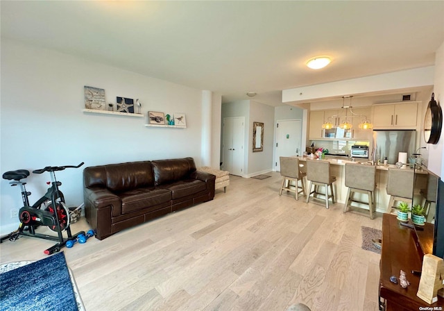 living room with light wood-type flooring and an inviting chandelier