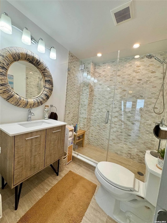 bathroom with tile patterned flooring, vanity, an enclosed shower, and toilet