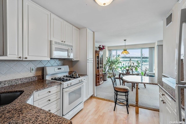 kitchen with light wood-type flooring, white appliances, white cabinets, and dark stone counters