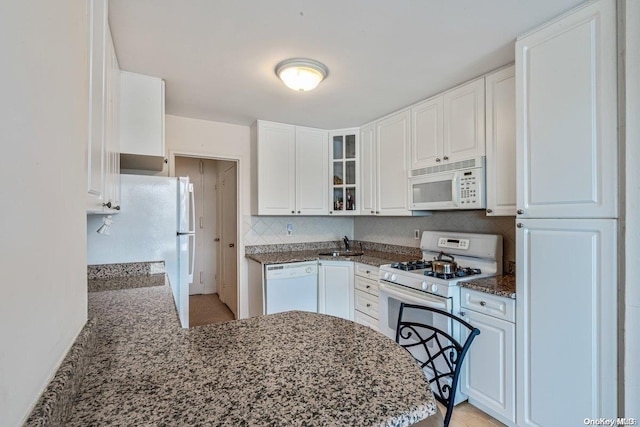 kitchen featuring white cabinets, white appliances, kitchen peninsula, and sink