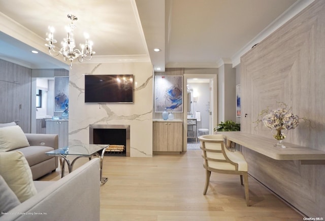 living room featuring a high end fireplace, an inviting chandelier, light wood-type flooring, and ornamental molding