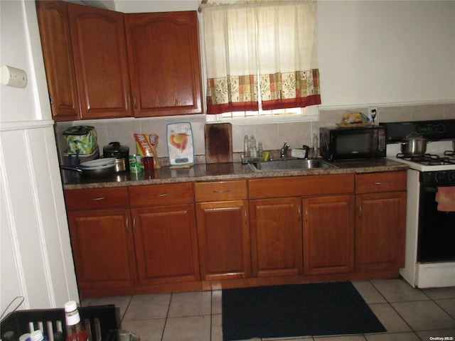 kitchen with decorative backsplash, sink, light tile patterned flooring, and white range