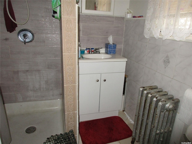 bathroom featuring radiator, vanity, a shower with shower door, and tile walls