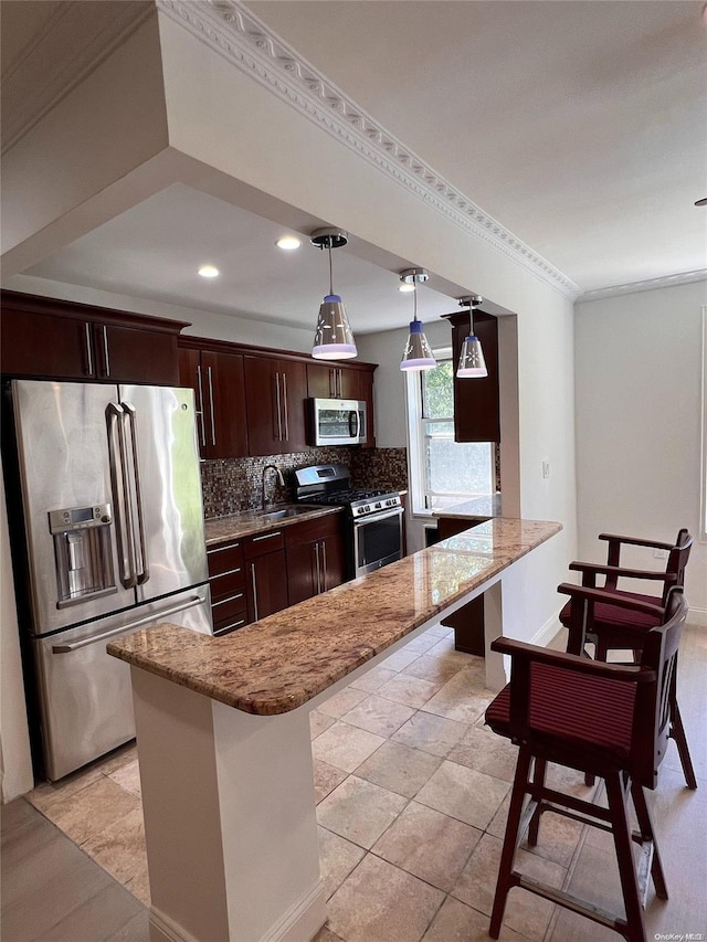 kitchen with stone counters, dark brown cabinets, a kitchen bar, kitchen peninsula, and stainless steel appliances