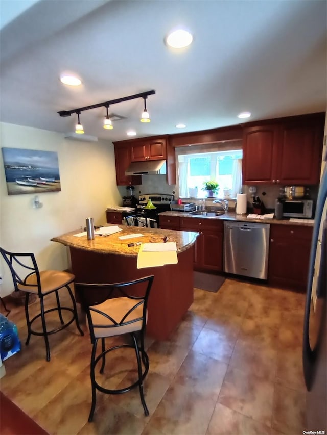 kitchen with sink, rail lighting, a center island, a kitchen bar, and appliances with stainless steel finishes