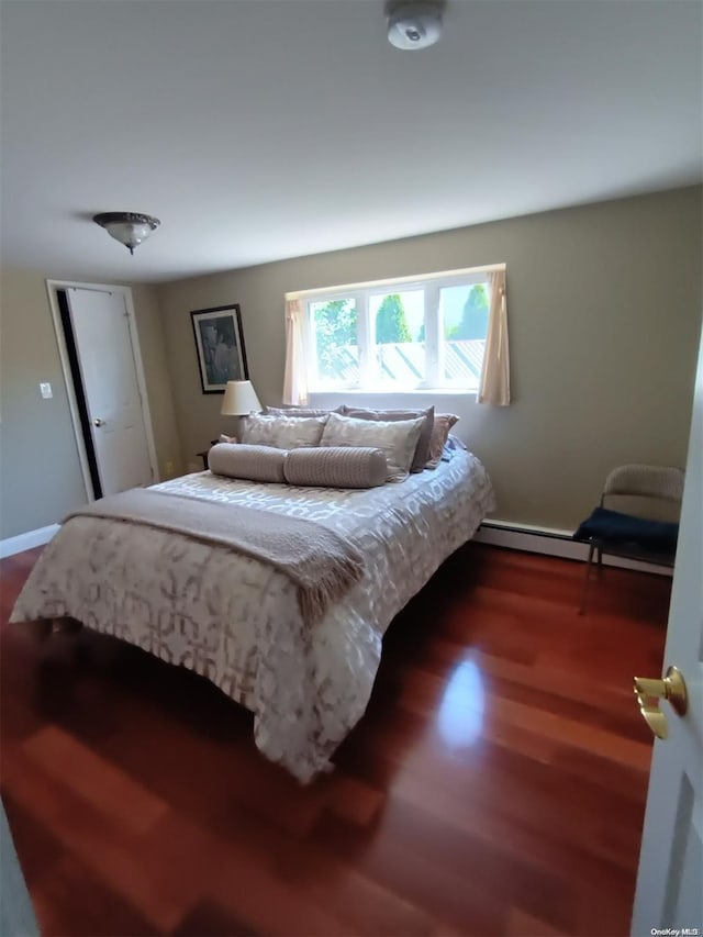 bedroom with baseboard heating and dark wood-type flooring