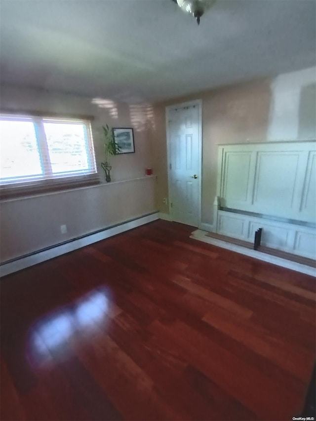 unfurnished room with hardwood / wood-style flooring and baseboard heating