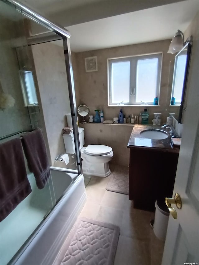 full bathroom with tile patterned flooring, vanity, toilet, and enclosed tub / shower combo