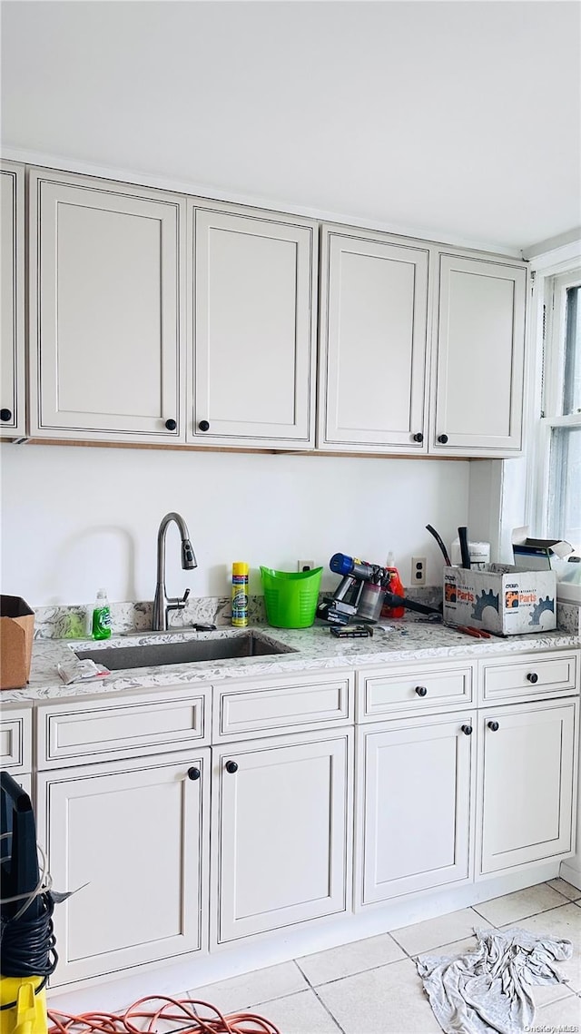 interior space featuring light stone counters, sink, and light tile patterned floors