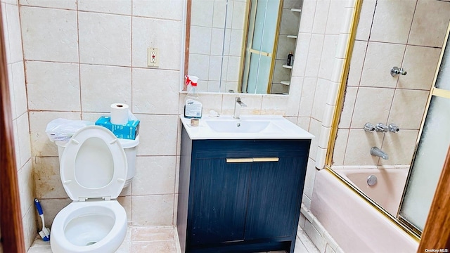 full bathroom with vanity, toilet, tile walls, and bath / shower combo with glass door